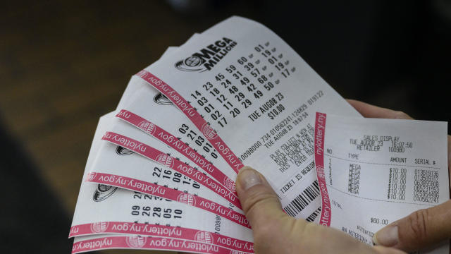 A person holds up their Mega Millions lottery tickets in New York City on Aug. 8, 2023. 