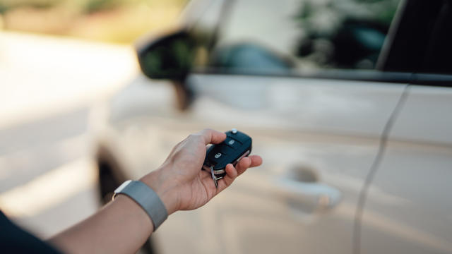 Female hand unlocking car with electronic car key 
