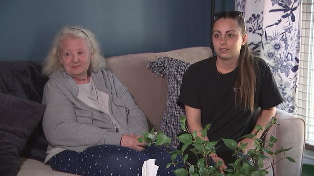 Karen Dipol and her granddaughter speak to a reporter about the fire; they are sitting on a couch in a home. 