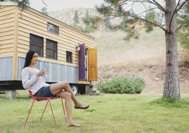 Young woman sitting outside her tiny house 