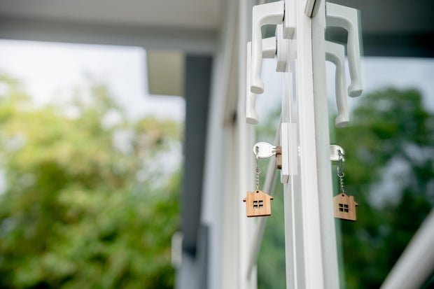 Landlord key for unlocking house is plugged into the door. Second hand house for rent and sale. keychain is blowing in the wind. mortgage for new home, buy, sell, renovate, investment, owner, estate