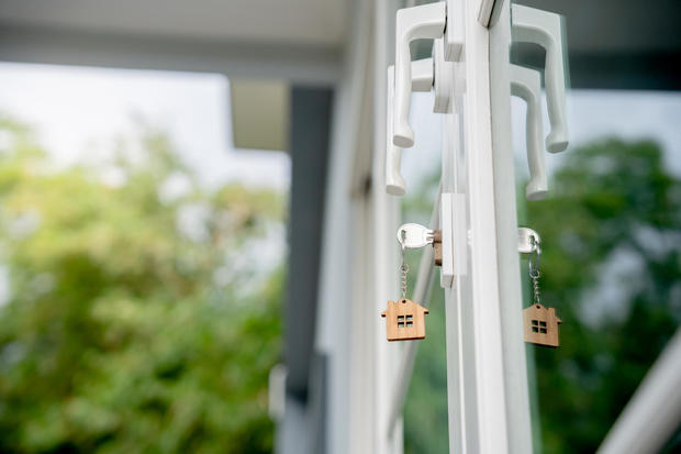 Landlord key for unlocking house is plugged into the door. Second hand house for rent and sale. keychain is blowing in the wind. mortgage for new home, buy, sell, renovate, investment, owner, estate 