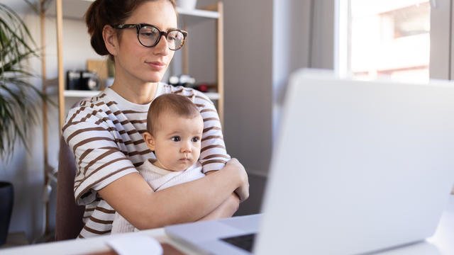 Focused mom working from her living room with baby in her lap 