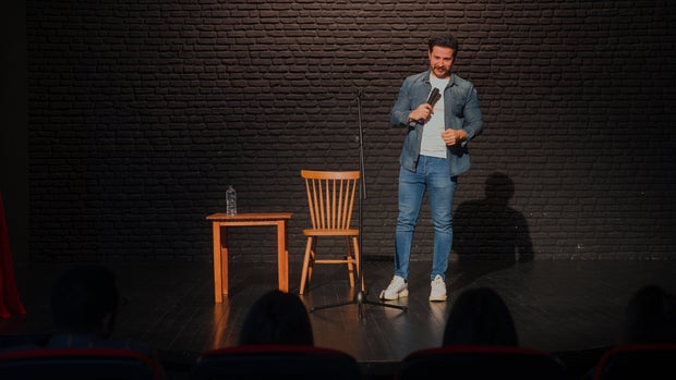 Male stand-up comedian talking on stage 