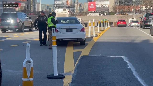 Two MTA Bridge and Tunnel officers stop a white Mercedes sedan outside the Queens Midtown Tunnel. 
