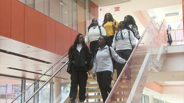 Six sisters walk down the stairs inside an Adelphi University building. 