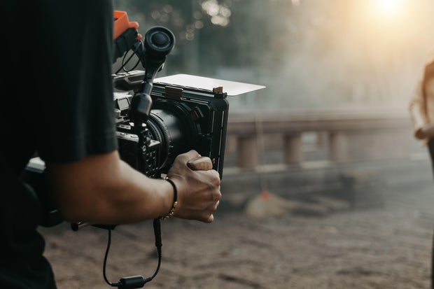 Close up hands holding cinema camera shooting 