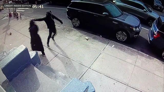 Surveillance video shows an individual punching a woman in the side of the head on a New York City sidewalk. 
