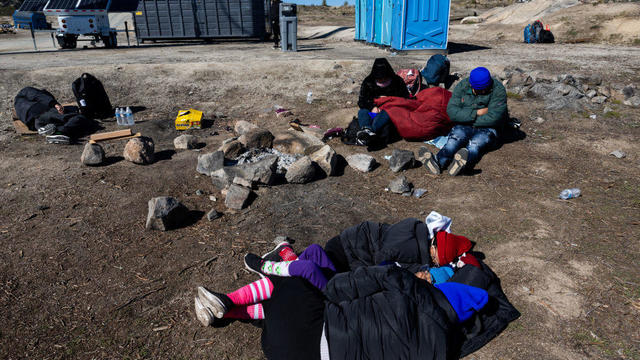 Migrants wait to be processed by the U.S. Border Patrol after crossing from Mexico at a makeshift camp next to the U.S. border wall on Feb. 13, 2024, in Jacumba Hot Springs, California. 