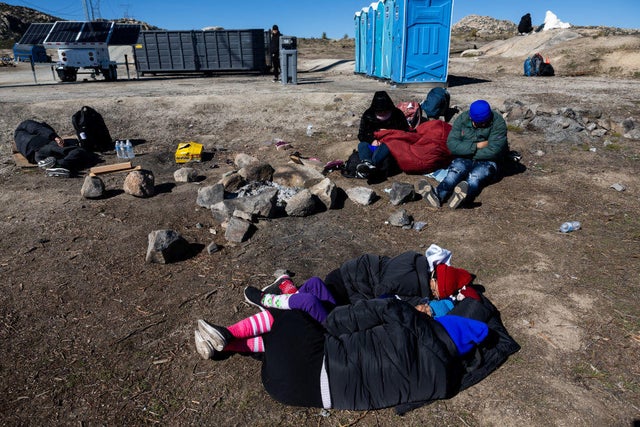 Migrants wait to be processed by the U.S. Border Patrol after crossing from Mexico at a makeshift camp next to the U.S. border wall on Feb. 13, 2024, in Jacumba Hot Springs, California. 