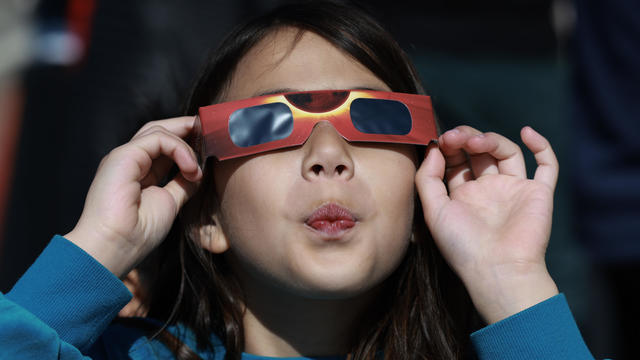 Miriam Toy looks through a pair of eclipse glasses that NASA was handing out as she awaits the eclipse on April 8, 2024, in Houlton, Maine. 