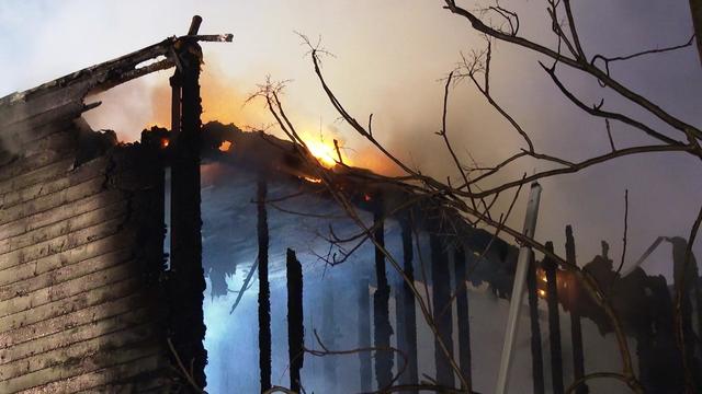 Flames can be seen on the top of a home in Newburgh. The exterior walls and roof have been destroyed and the charred framework of the home can be seen. 