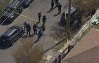 An aerial view of police officers standing on a residential street near crime scene tape. 