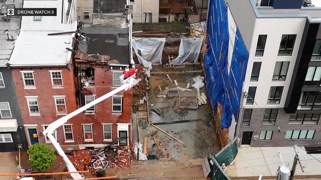 Aerial photo of a rowhome next to an empty lot, the home is partially collapses and crews are working in the area 