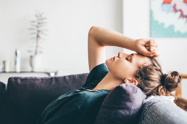 Sad and depressed woman sitting on sofa at home. 