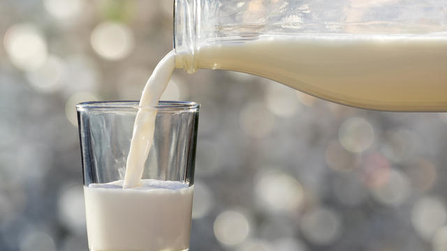 Bottle of milk of crystal filling a glass of milk, illuminated by the natural light of the Sun 