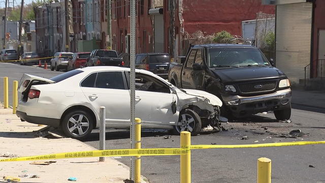 A white sedan and a black pick-up truck are seen after an accident in North Philadelphia, yellow police tape marks off the scene 