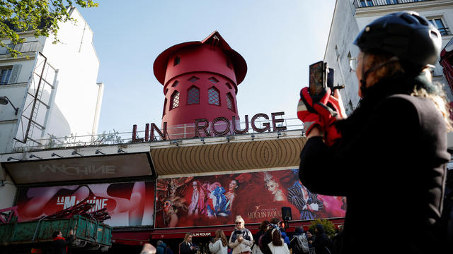 People take pictures of the landmark red windmill atop the Moulin Rouge, Paris' most famous cabaret club, after its sails fell off during the night in Paris 