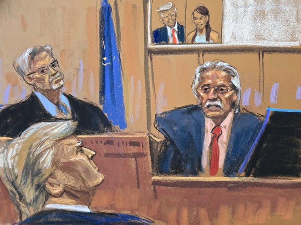 Former President Donald Trump looks on as David Pecker testifies in front of an image of Trump and Karen McDougal during Trump's criminal trial in New York on Thursday, April 25, 2024.