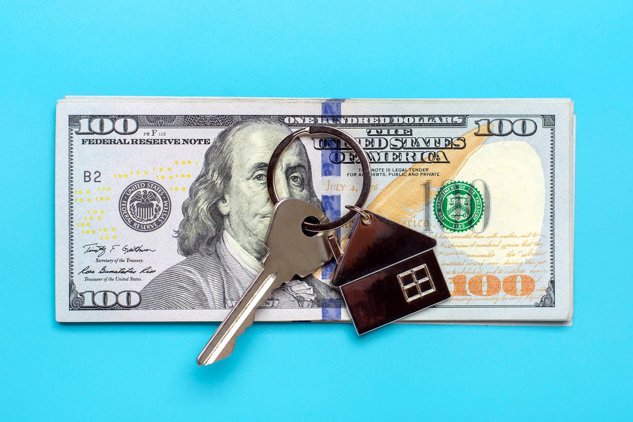 house or apartment key, dollars banknote isolated on blue background 