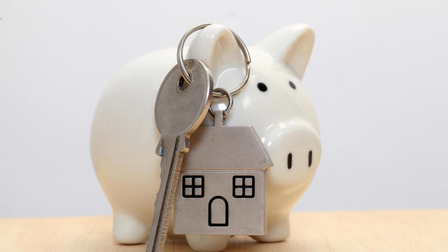 Piggy bank and house key against white background 