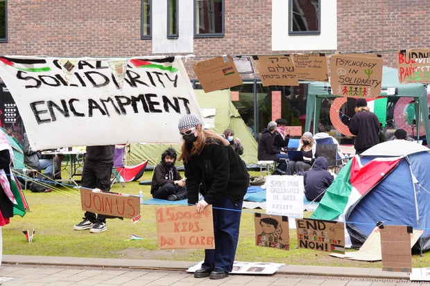 A student adjusts a sign at a camp on the grounds of Newcastle University, protesting against the war in Gaza, on May 2, 2024. Students from universities in Leeds, Newcastle and Bristol set up tents outside university buildings, replicating the national demonstrations in campus that started in the USA
