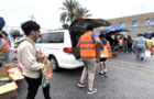 Volunteers place grocery items in the car trunks of recipients 