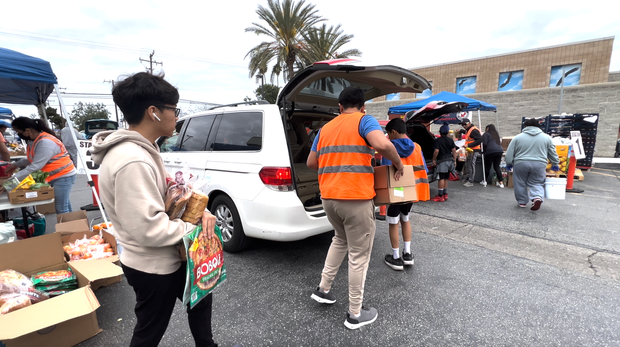 Volunteers place grocery items in the car trunks of recipients