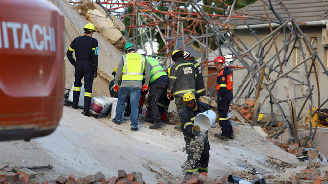 Rescuers work to rescue construction workers trapped under a building that collapsed in George 