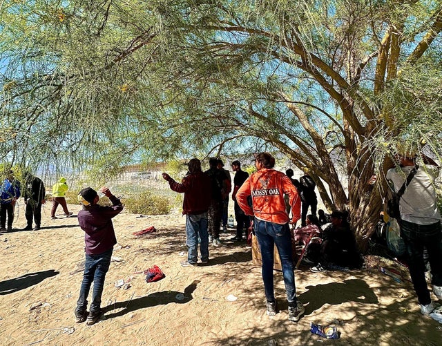 Migrants waiting to enter the U.S. huddle under a tree in Ciudad Ju&aacute;rez on Tuesday, April 30, 2024. 