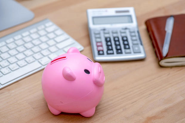 Savings and investment concept, pink piggy bank with calculator on pile or economic analysis report chart and graph on office table. 