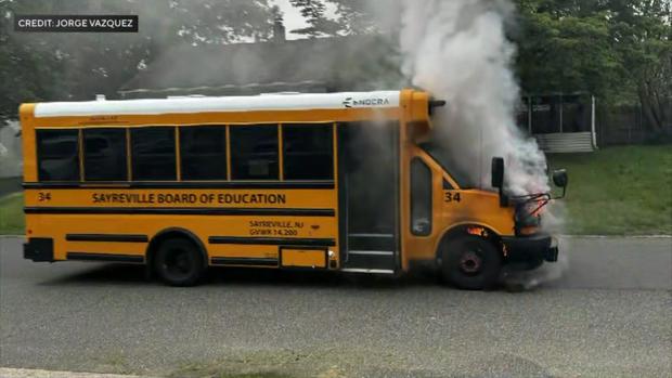 A photo shows gray smoke pouring from the front of a short Sayreville school bus. 