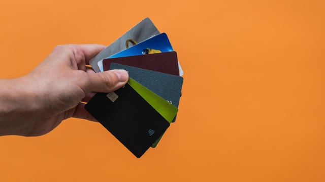 Hand with a lot of credit cards with copy space on orange background 