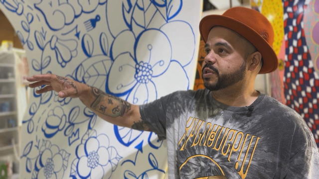 The artist Roberto Lugo gestures toward one of the 12-foot sculptures that will be installed in Philadelphia 