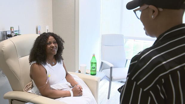 A woman receiving cancer treatment is seen talking to Andrea Ross, in a hospital room 