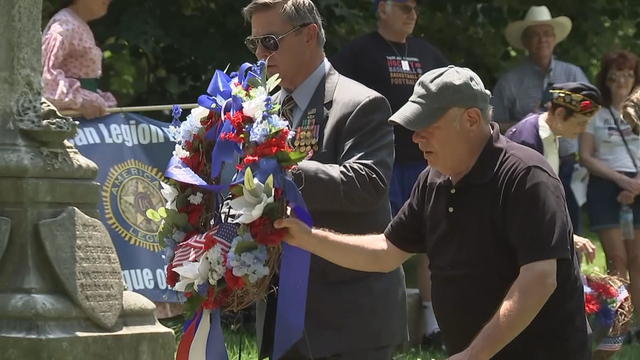 Two men present a red, white and blue wreath at a Memorial Day evemt 