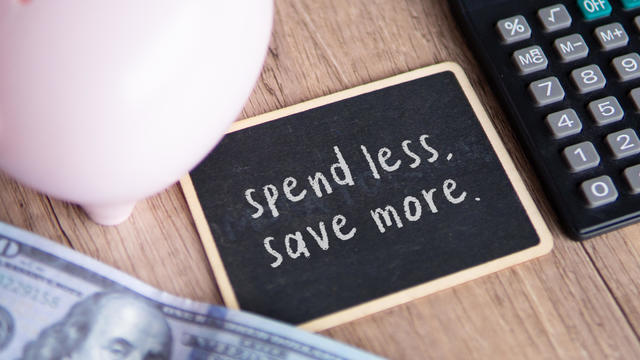 Top view image of chalkboard with text SPEND LESS, SAVE MORE. 