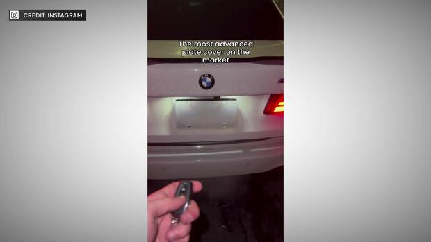 A screenshot of an Instagram video shows the back of a white BMW. A license plate cover obscures the license plate number. The caption reads "The most advanced plate cover on the market." 