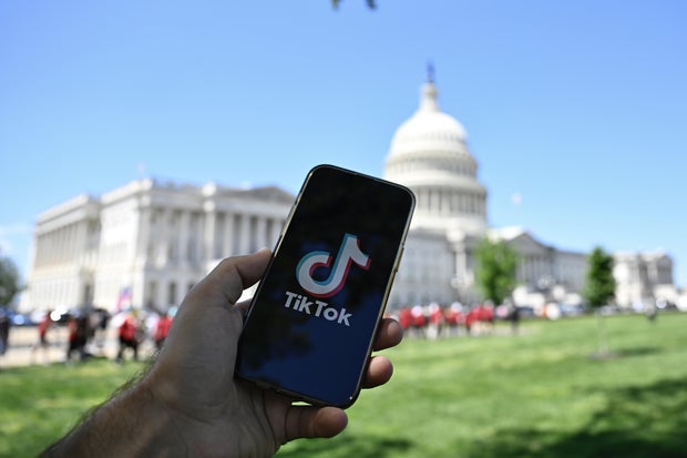 The logo of TikTok is displayed on a mobile phone screen in front of The White House in Washington DC, United States on April 20, 2024.