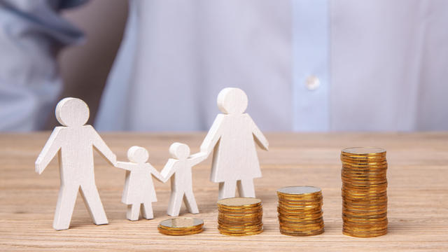 Growth of the family budget. Man holds family from his father, mother, daughter and son against the background of stack of coins 