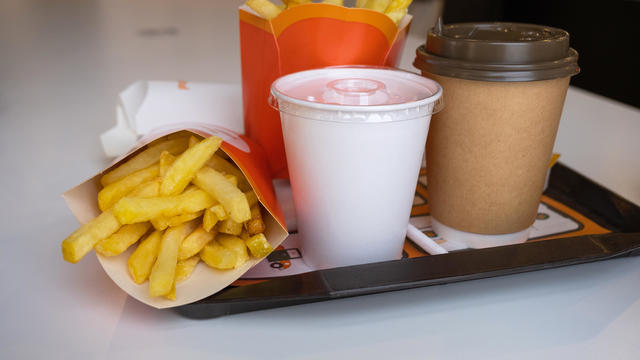 Fast food on a tray in a restaurant. French fries, a glass with a milkshake, coffee 