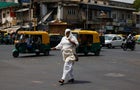 A woman covered with a cloth to protect herself from the heat walks on a road during a heatwave in Ahmedabad 