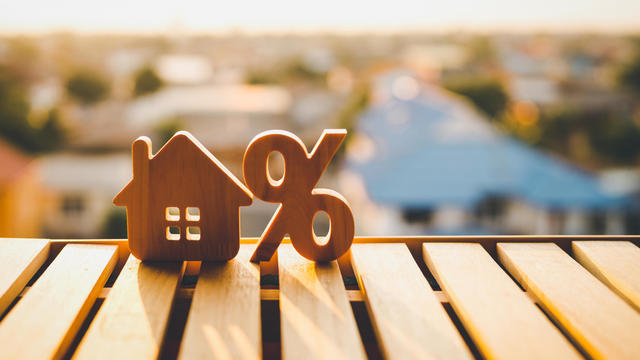 Percentage and house sign symbol icon wooden on wood table. Concepts of home interest, real estate, investing in inflation. 