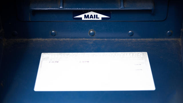 close up front view of traditional blue postal mailbox slot & handle 