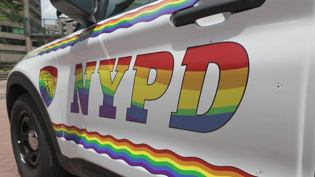 The side of an NYPD vehicle features wavy rainbows and the letters "NYPD" in rainbow colors. 