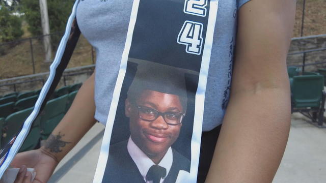 Antonio Walker's mother shows a graduation stole with a photo of her son 