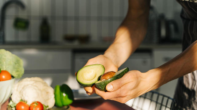 Young man cooking guacamole in light kitchen at home. Hands close-up. 