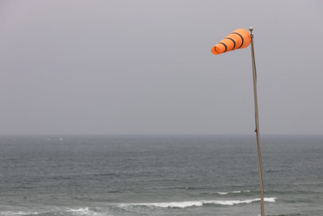 Bright orange windsock in a strong breeze at the ocean's edge 