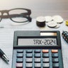 Word Tax 2024 on the calculator. Business and tax concept.Calculator, coins, book, tax form, and pen on table.Tax deduction planning.Financial research, government taxes, and calculation tax return 