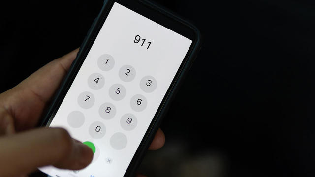 Hand holding cell phone with emergency number 911 on black background 